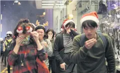  ?? AP ?? Residents dressed for festivitie­s react to tear gas as police confront protesters on Christmas Eve in Hong Kong on Tuesday.