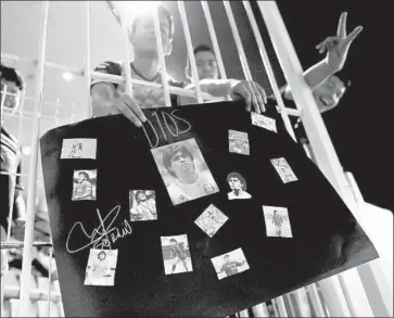  ?? Gary Coronado Los Angeles Times ?? SOCCER FAN Juan Soto, 17, holds a collage of photos of Argentine legend Diego Maradona with the word dios (god) before the start of a recent match. Under Maradona, the Dorados have clinched a playoff spot.