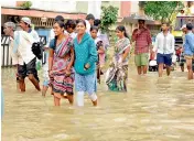  ?? — DEEPAK DESHPANDE ?? Residents of Nizampet walk on the flooded streets even as they wait for relief to arrive on the fourth day of heavy rains in Hyderabad on Saturday.