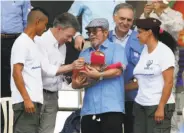  ?? Fernando Vergara / Associated Press ?? President Juan Manuel Santos (second left) and rebel chief Rodrigo Londoño smile over a baby.