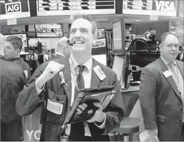  ?? Justin Lane European Pressphoto Agency ?? A TRADER on the floor of the New York Stock Exchange reacts after the Dow closed above 20,000. Others celebrated by wearing baseball caps emblazoned with “Dow 20,000.” Trump responded with a tweet: “Great!”