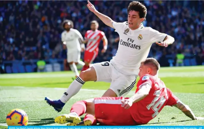  ?? —AFP ?? MADRID: Real Madrid’s Spanish defender Alvaro Odriozola (back) challenges Girona’s Spanish defender Raul Garcia during the Spanish League football match between Real Madrid and Girona at the Santiago Bernabeu stadium in Madrid yesterday.