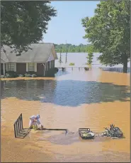  ?? Arkansas Democrat-Gazette/STATON BREIDENTHA­L ?? Matthew Fogle unloads sandbags from his nearly submerged trailer Saturday in the 12000 block of Willow Beach Road in North Little Rock after getting stuck in high water while trying to take them to a neighbor’s house.