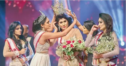 ??  ?? Winner of Mrs. Sri Lanka 2020 Caroline Jurie (2-L) removes the crown of 2021 winner Pushpika de Silva (C)