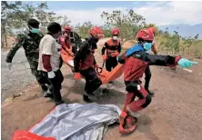  ??  ?? SOMBER TASK: Rescue workers, above and right, carry bodies to be buried at a mass grave for victims.