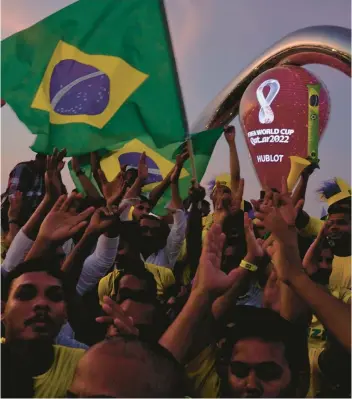  ?? JON GAMBRELL/AP ?? Fans cheer and wave Brazilian flags on Friday in front of the World Cup countdown clock in Doha, Qatar. Fans poured in ahead of the Middle East’s first World Cup.