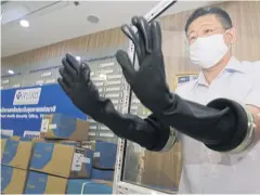  ?? APICHIT JINAKUL ?? A doctor tests out gloves at the National Health Security Office, which received a donation of 4,000 protective items and 25,000 N95 face masks.