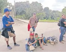  ??  ?? Héctor Torres y su familia, procedente­s de Honduras, esperan en la carretera un aventón para llegar a Veracruz; han gastado en pasajes unos 500 dólares.