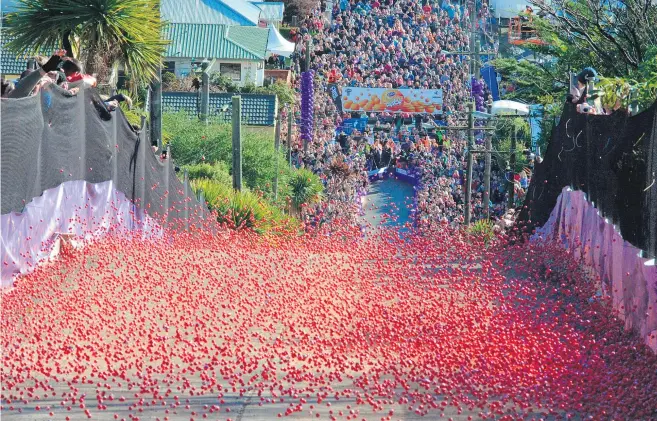  ?? Pictures / Otago Daily Times ?? It’s a sea of red as Jaffas of the chocolate variety race down the world’s steepest street in Dunedin yesterday.