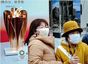  ?? AFP ?? People wearing face masks take pictures in front of the Tokyo 2020 Olympic flame displayed outside the Miyako railway station in Iwate prefecture on Sunday, after its arrival from Greece. —