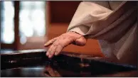  ?? The New York Times/STEPHEN HILTNER ?? The Rev. Stan Gumula, the abbot of Mepkin Abbey, dips his hand in holy water at Vespers at the Trappist monastery.