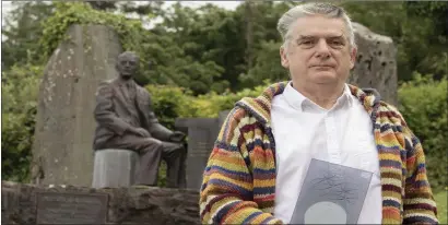  ??  ?? Peadar Ó Riada, pictured with his Cork Person of the Month award, in the church yard in Cúil Aodha. Peadar and Cór Chúil Aodha have been singing at socially distanced Masses every Sunday during COVID-19. These are broadcast on Facebook.