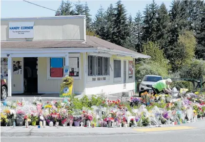  ?? Photo / AP ?? A community in Puyallup, Washington, is expressing support and grief after the killing of a shopkeeper. David Berry places flowers on a still-growing memorial outside the Handy Corner Food Store. Soon Ja Nam, 79, who had operated it with her husband since 1979, was shot and killed last weekend during a robbery.