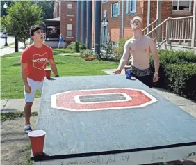  ?? ERIC ALBRECHT/USA TODAY NETWORK ?? OSU students Max Anderson, left, and Alejandro Pimenteo play a drinking game outside on Aug. 11. The students expressed disappoint­ment that the football season was canceled.