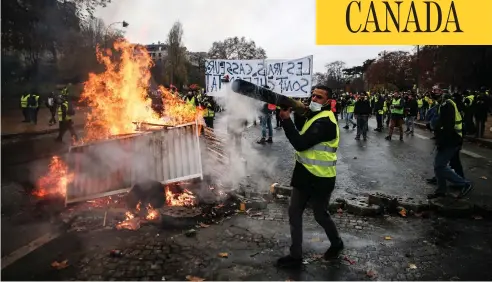  ?? ABDULMONAM EASSA / AFP / GETTY IMAGES ?? “Yellow vest” protesters in Paris build a barricade during a protest against rising oil prices and living costs on Saturday that sparked rioting.