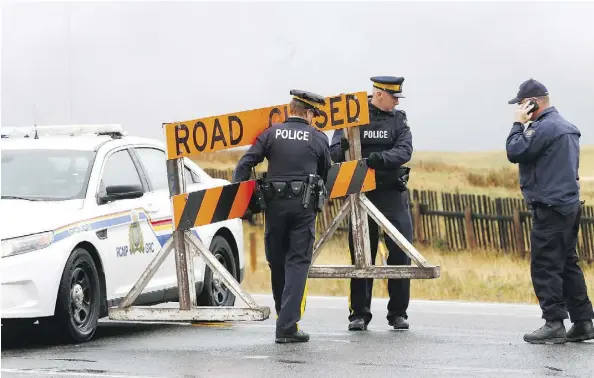  ?? DARREN MAKOWICHUK ?? RCMP officers take down the road block at Highway 6 and 505 Thursday as rain and cold weather in the Pincher Creek area shrank the evacuation zone near Waterton Park. Homes and businesses within the Waterton townsite are untouched, but the park...