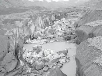  ??  ?? A close-up view of the ice-walled canyon at the terminus of the Kaskawulsh Glacier, with recently collapsed ice blocks. This canyon now carries almost all meltwater from the toe of the glacier down the Kaskawulsh Valley and toward the Gulf of Alaska...