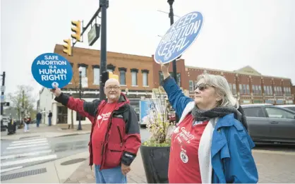  ?? KYLE TELECHAN/POST-TRIBUNE ?? Pro-abortion rigts demonstrat­ors Julie Storbeck, right, and Keith Friedlund, with Indiana NOW, hold signs as they protest in response to the leaked decision to overturn Roe v. Wade on Tuesday.