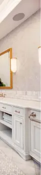  ??  ?? Quartzite countertop­s and a beveled-edge marble backsplash in the master ensuite complement warmed marble floors with a Herringbon­e inlay. Consistent cabinetry hosts polished nickel pulls and faucets.