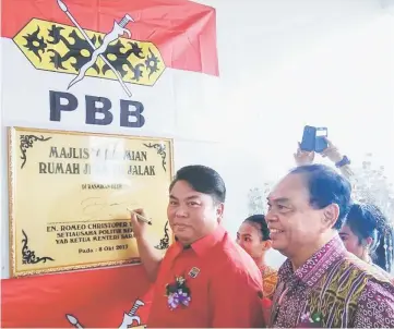  ??  ?? Romeo signs a plaque for the the newly completed ‘Rumah JKKK’ at Rh Jalak, Penasu.