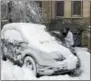  ??  ?? Troy resident Misty Feist brushes snow off her car Friday morning along 2nd Street in downtown Troy.