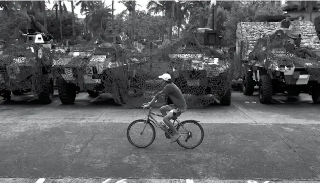  ?? (AFP) ?? A man cycles past armoured personnel carriers parked near the venue of the 31st Southeast Asian Nations (ASEAN) Summit at the Philippine internatio­nal convention centre in Manila on November 10, 2017. World leaders are set arrive in Manila on November...