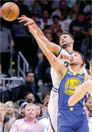  ??  ?? Denver Nuggets guard Jamal Murray passes the ball away from Golden State Warriors guard Stephen Curry during the first quarter of an NBA basketball game in Denver. ASSOCIATED PRESS