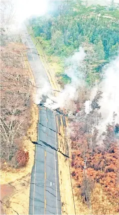  ??  ?? Aerial view of ground cracks on a road during an overflight of the eruptrive fissure area following eruption of Kilauea volcano, Hawaii.