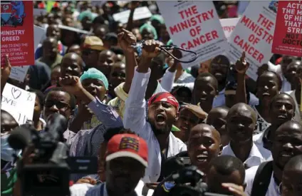  ??  ?? In this Feb. 15 file photo, a striking doctor holds his stethoscop­e in the air as he and other medical staff protest the detention of their union leaders, outside an appeal court in Nairobi, Kenya. Thousands of doctors at Kenya’s public hospitals have...