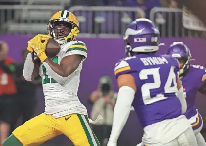  ?? BRUCE KLUCKHOHN/AP ?? The Packers’ Jayden Reed catches a touchdown pass in front of the Vikings’ Camryn Bynum during the first half on Dec. 31 in Minneapoli­s.