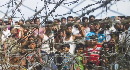  ?? AFP PHOTO ?? PROBE AT LAST
Rohingya refugees gather behind a barbed-wire fence in a temporary settlement setup in a ‘no man’s land’ border zone between Myanmar and Bangladesh. The Internatio­nal Criminal Court gave the green light for a long-awaited full probe into Myanmar’s alleged crimes against Rohingya Muslims, including violence and forced deportatio­ns.