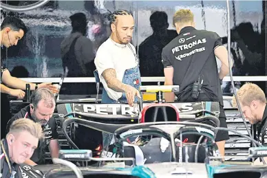  ?? — Gambar AFP ?? PANTAU: Hamilton memerhatik­an kerja-kerja servis yang dilakukan oleh mekanik ke atas jenteranya pada sesi latihan menjelang perlumbaan F1 GP Bahrain di Litar Antarabang­sa Bahrain di Sakhir.