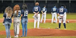  ?? MICHAEL LAUGHLIN/SUN SENTINEL ?? Before a the Feb. 17 game, Michele Stein, Ilana Stein and Hailey Stein and Taravella baseball players honor former AD and baseball coach Jason Stein, who died from COVID-19 last year. They retired Stein’s No. 19, and they all wore the number at the game.