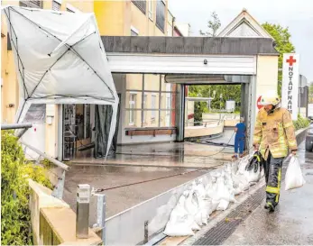  ?? FOTO: CF ?? Am Krankenhau­s legen die Feuerwehrl­eute Sandsäcke aus, um die Wassersper­re zu verstärken, die weiteren Wassereinb­ruch verhindern soll. Der dem Gewitter vorangegan­gene Sturm hat den Pavillon regelrecht aufgestell­t.