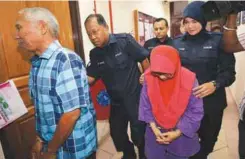  ??  ?? Muslim and his wife being taken to the sessions court in Ipoh yesterday to face 12 charges of exploitati­on of children.