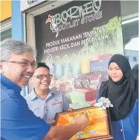  ??  ?? RASMI: Samat (kiri) menurunkan tandatanga­nnya pada plak sempena majlis perasmian premis Borneo Outlet Store (BOS) di Pusat Komersil Miri Waterfront semalam, sambil disaksikan Hafidz (tengah).
