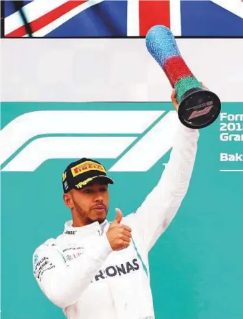  ?? Reuters ?? Mercedes’ Lewis Hamilton celebrates with the trophy on the podium after winning the race at the Azerbaijan Grand Prix in Baku City Circuit yesterday.