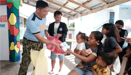  ?? PHOTOGRAPH BY JASPER JAY DAWANG FOR THE DAILY TRIBUNE ?? MEMBERS of the Ilocos Norte Police Provincial Office hand out food packs and hygiene kits to evacuees in Lanao, Bangui who were forced out of their homes due to the onslaught of typhoon ‘Betty’ in Northern Luzon.