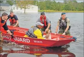  ?? Chris Megerian Los Angeles Times ?? COAST GUARD rescuers and a Jones County sheriff ’s deputy push Alonzo Harris and his dog through floodwater­s after rescuing them in Trenton, N.C.