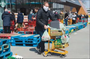  ?? Canadian Press photo ?? Long lines of masked shoppers wait to shop for groceries in Toronto in this April file photo. As Ontario municipali­ties enact new measures regarding the use of masks in commercial locations, business owners are on their own when it comes to dealing with customers who refuse to comply.