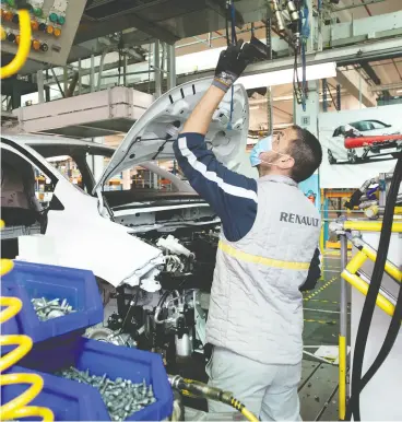  ?? Christophe Morin / Bloomberg files ?? An employee wearing a protective face mask works on the Renault Zoe electric automobile assembly line in Flins, France. The car industry employs 400,000 people in
France, with roughly 30 vehicle and parts factories dotted across the country.