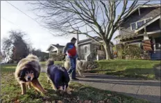  ??  ?? In this Dec. 13, 2017, photo, a man walks dogs though a single-family neighborho­od dotted with bungalows and stately Craftsman homes, where a proposal would allow houses to be built three-tofive stories high in Seattle. AP PHOTO/ELAINE THOMPSON