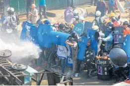  ?? GETTY-AFP ?? People protesting last month’s coup take cover behind makeshift shields while being drenched by a water cannon fired at them by police Tuesday in Kale, Myanmar.