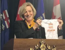  ?? MARIAM IBRAHIM/ EDMONTON JOURNAL ?? Premier Rachel Notley holds up a onesie emblazoned with a quote from the late federal NDP leader Jack Layton. The onesie is destined for Calgary- Varsity NDP MLA Stephanie McLean, who will deliver her first child in February.