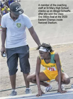  ??  ?? A member of the coaching staff at St Mary High School checks up on Abigail Schaaffe after she won the Class
One 800m final at the 2020 Eastern Champs inside National Stadium.