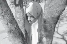  ??  ?? Hassan’s granddaugh­ter Ladan, 13 stands behind a tree as guests visit their home in Dagahaley, in the Dadaab Refugee Camp in northern Kenya.