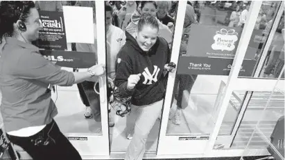  ?? GREG KAHN/AP ?? A woman bursts through the doors of a Kohl’s department store as it opened in Naples, Fla., on Black Friday last year.