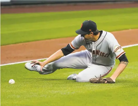  ?? Elaine Thompson / Associated Press ?? Giants starting pitcher Kevin Gausman slides across the infield to field a grounder by the Mariners’ Ty France in Thursday’s opener.