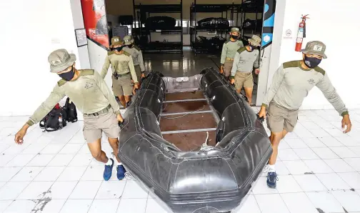  ?? DIPTA WAHYU/JAWA POS ?? SIAGA: Anggota Batalyon Intai Amfibi 2 Marinir menggotong perahu yang digunakan untuk penanganan warga tenggelam.