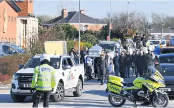  ??  ?? ● Police stop the traffic for the funeral procession outside the church